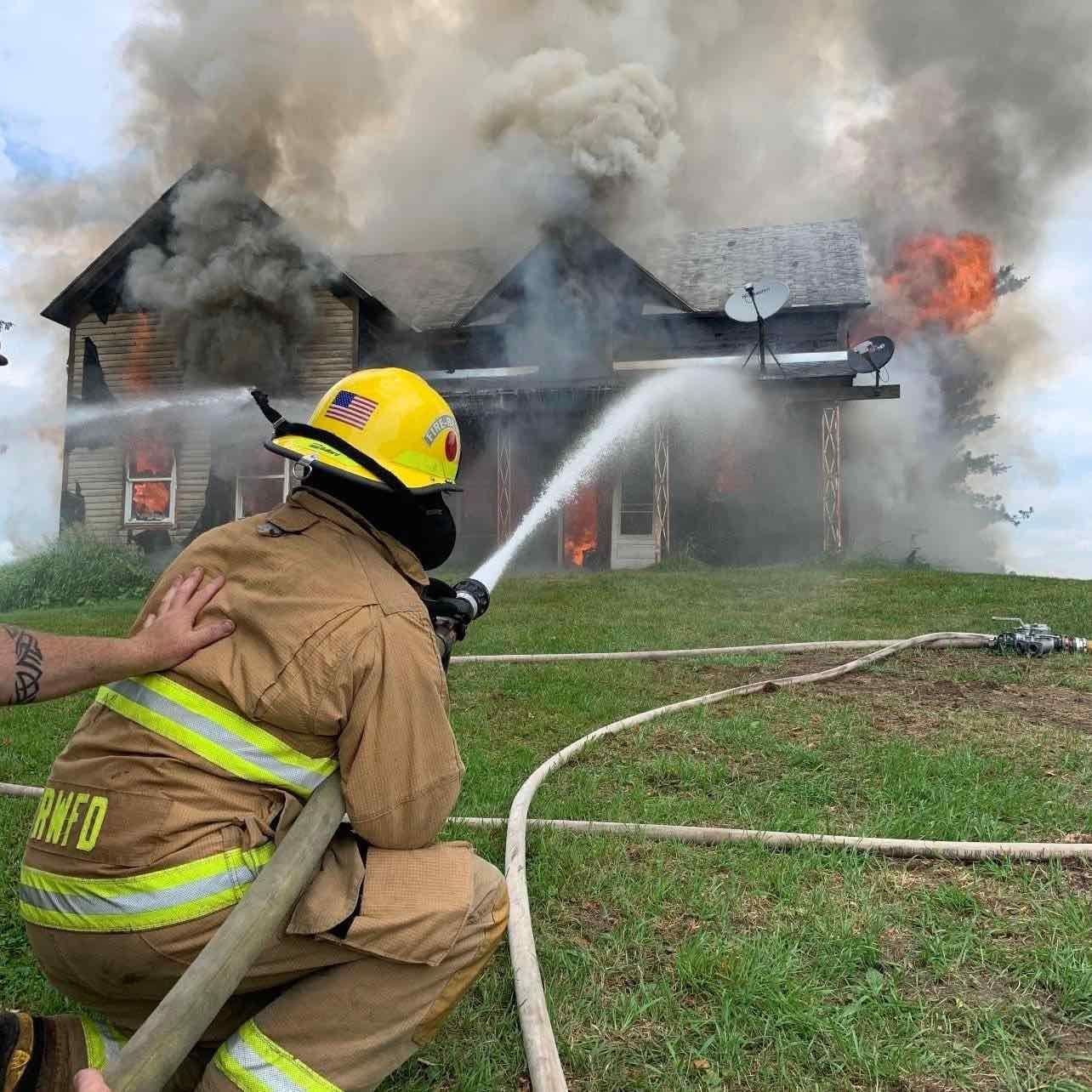 Roberts-Warren firefighter working a hose line at a structure fire
